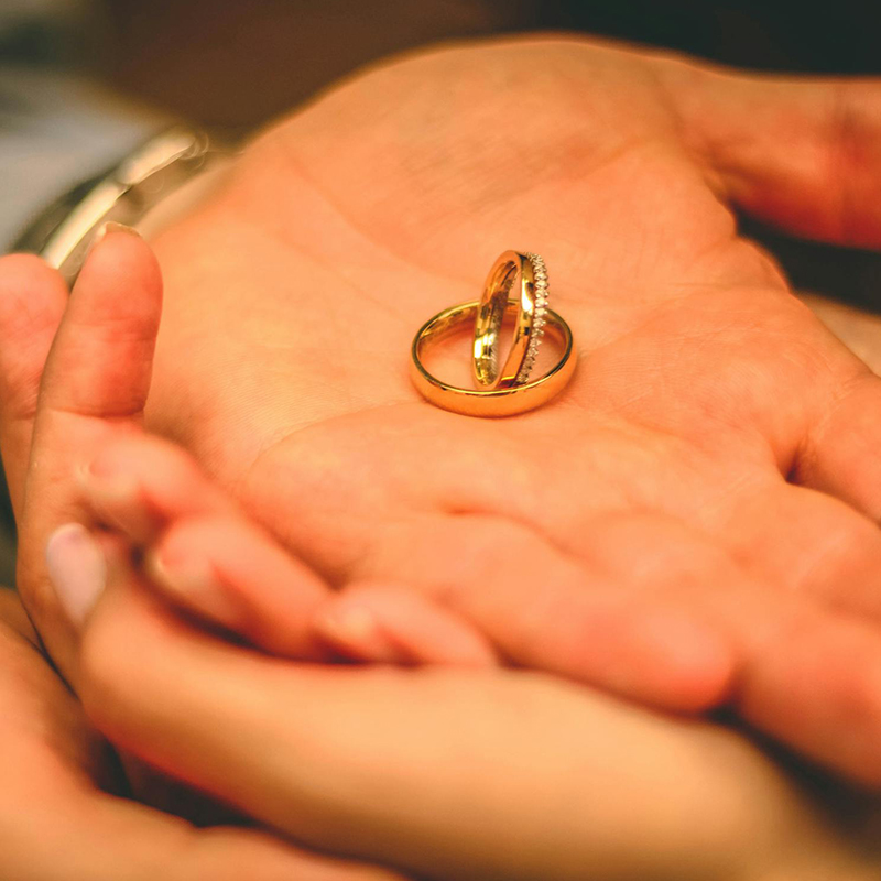 Two gold wedding bands nestled in the couple's hands