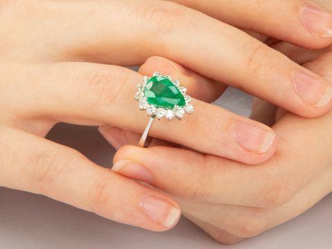 Emerald ring with diamond halo on hand