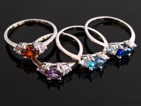 Four elegant gemstone rings on black background