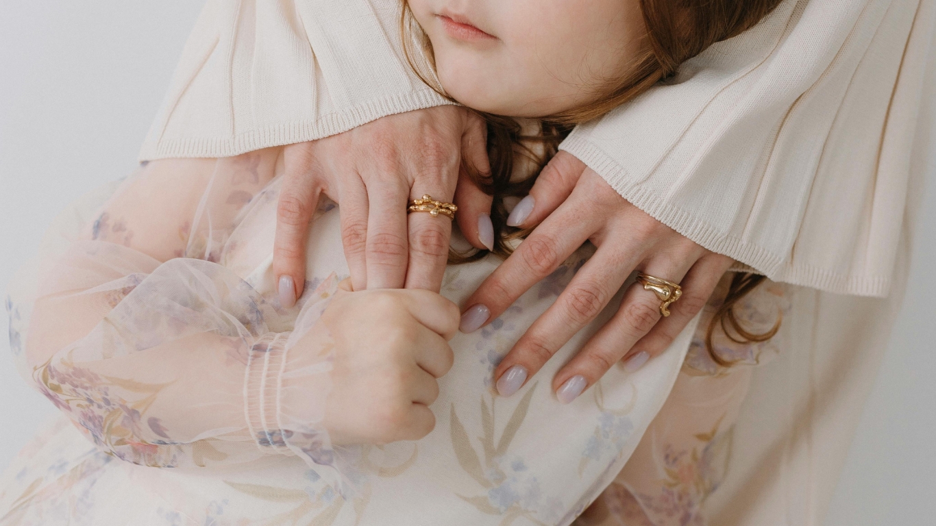 Mother and daughter embrace wearing gold rings.