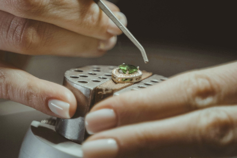 2 A close-up image of a jeweler’s hands carefully setting a gemstone into a piece of jewelry.