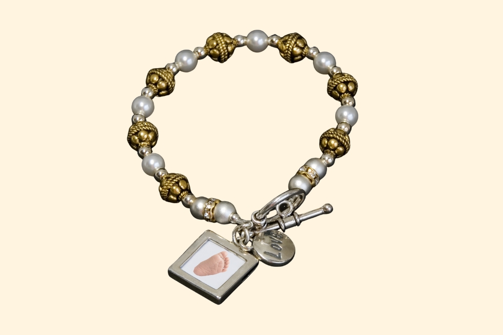 2 Pearl and gold bracelet with footprint charm.
