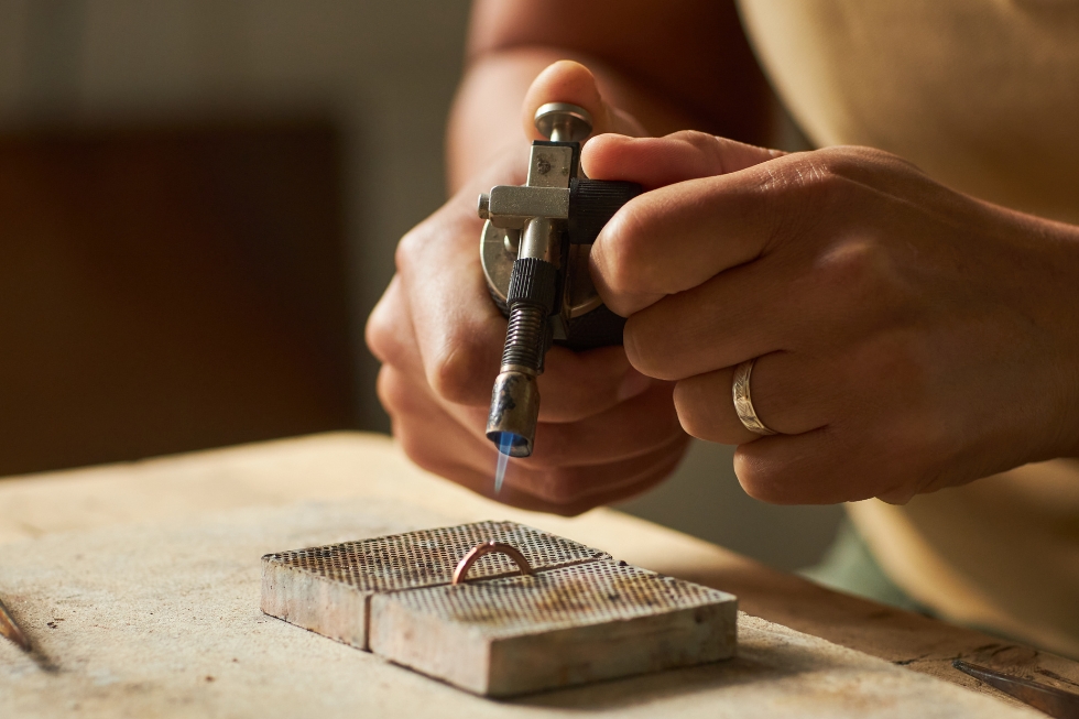 2 Close-up of jeweler using blowtorch to solder a ring.