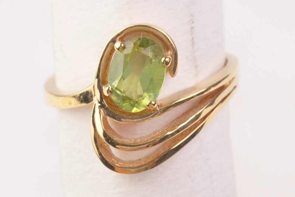 3 A close-up image of a gold ring featuring an oval-cut peridot gemstone.