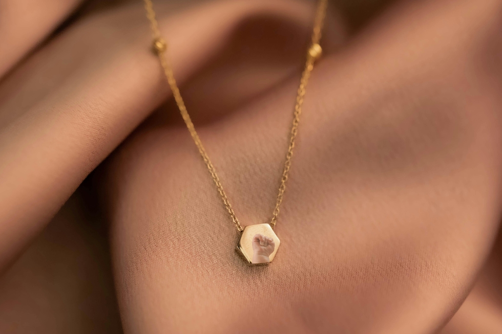3 Gold necklace with hexagonal handprint pendant.
