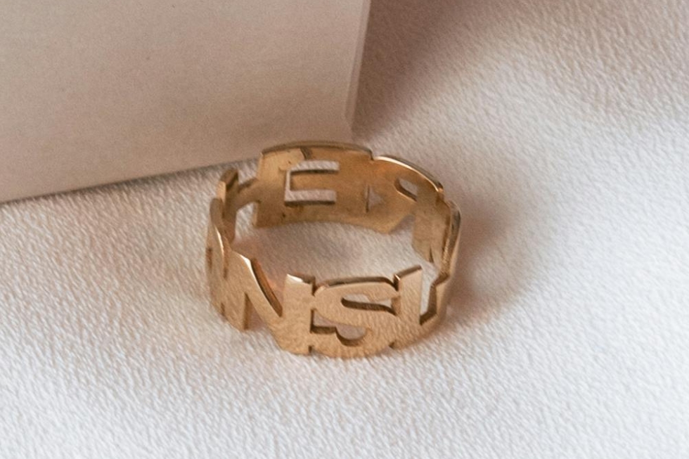 4 Gold ring with cut-out letters forming a continuous pattern.