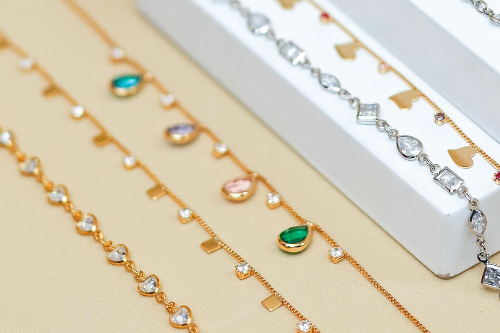 4 Close-up of delicate gold bracelets with colorful gems.