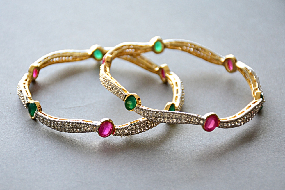 4 Pair of ornate gold bangle bracelets featuring alternating oval-cut pink rubies and green emeralds.
