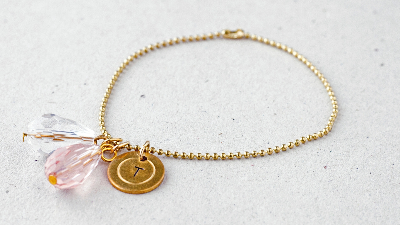 A small circular charm engraved with the letter "T".