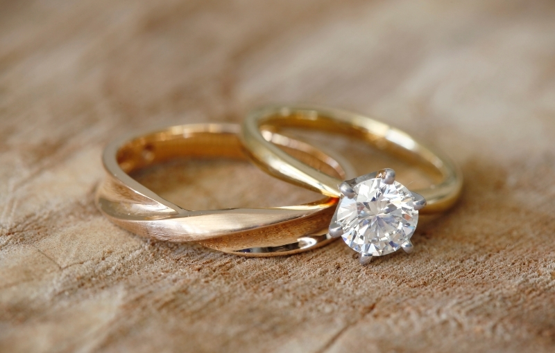 2 Close-up of wedding rings and diamond is set in a yellow gold engagement ring.