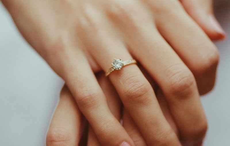 Hand with engagement ring on finger.