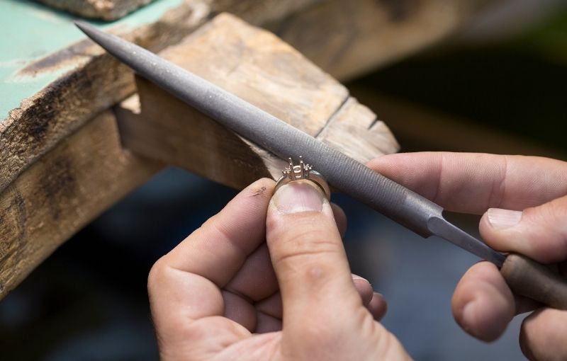 Jeweler handcrafting ring with file.