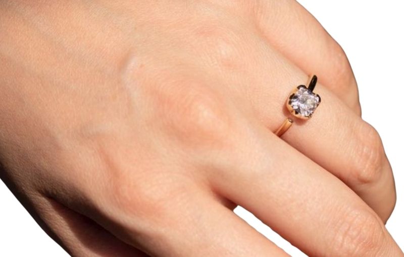 Hand wearing gold ring with cushion-shaped old mine cut diamond.