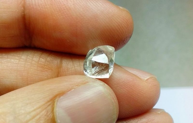 Raw diamond held between fingers.