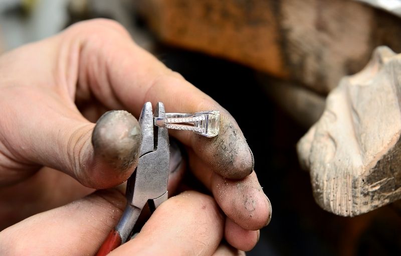Jeweler setting diamond ring with pliers.