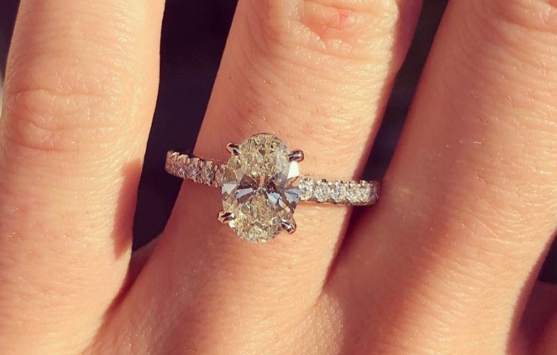 Oval diamond engagement ring on finger.