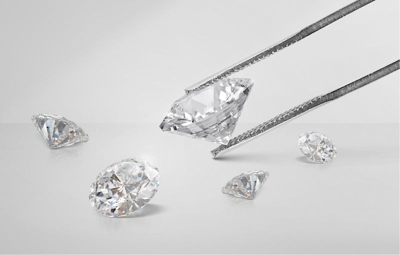 Loose round-cut diamonds with tweezers.