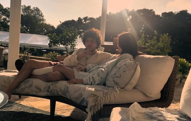 Selena Gomez and Benny Blanco relaxing together on outdoor lounger.