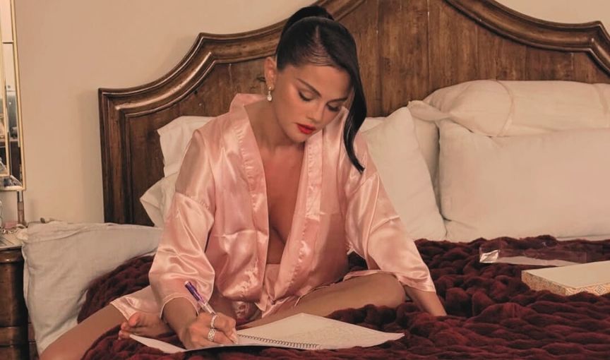 Selena Gomez in pink robe writing vows.