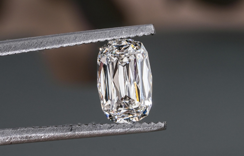 Emerald cut diamond in tweezers.