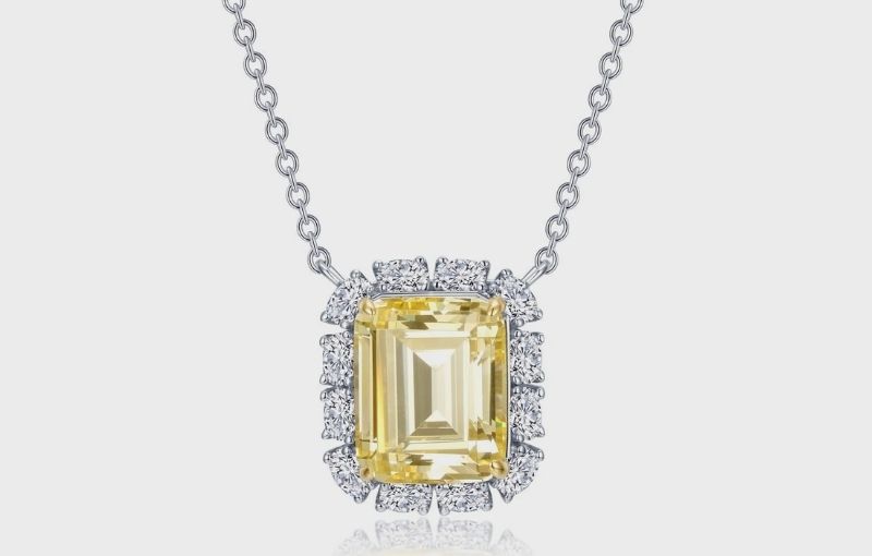 Yellow emerald-cut diamond halo necklace.
