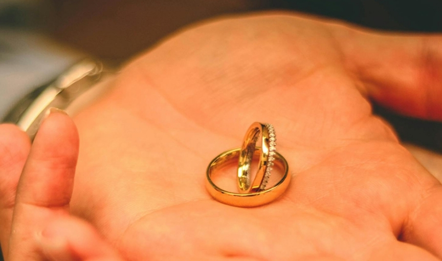 Gold wedding rings resting on palm, romantic jewelry shot