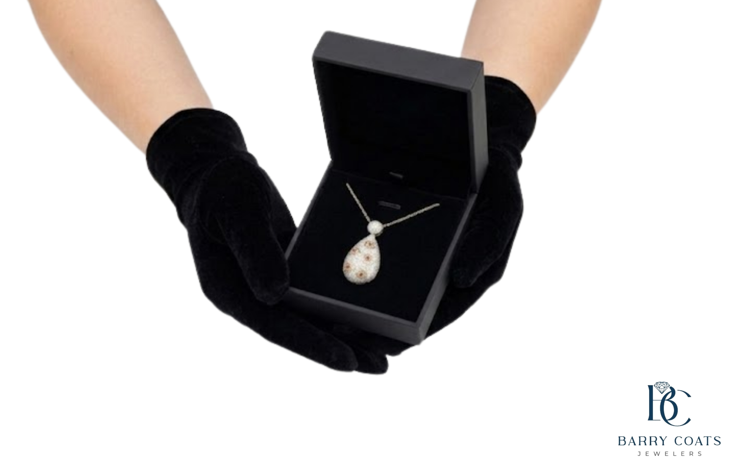 Diamond teardrop pendant displayed in jewelry box White gold diamond pavé eternity ring close-up