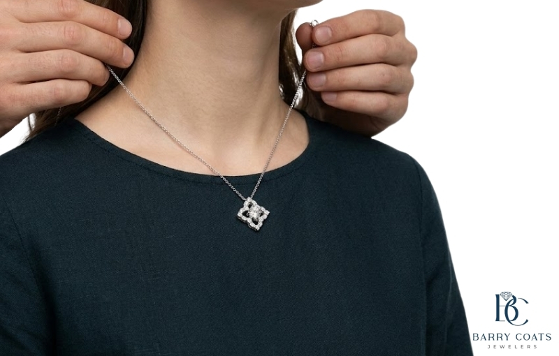 Person clasping a silver diamond pendant necklace Diamond pavé wedding band on bride's hand