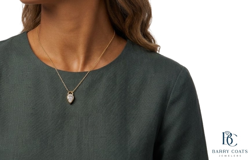Woman wearing a gold teardrop diamond pendant Diamond pavé wedding band on bride's hand